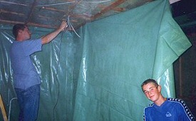 James stapling sheets of plastic over the insulation.